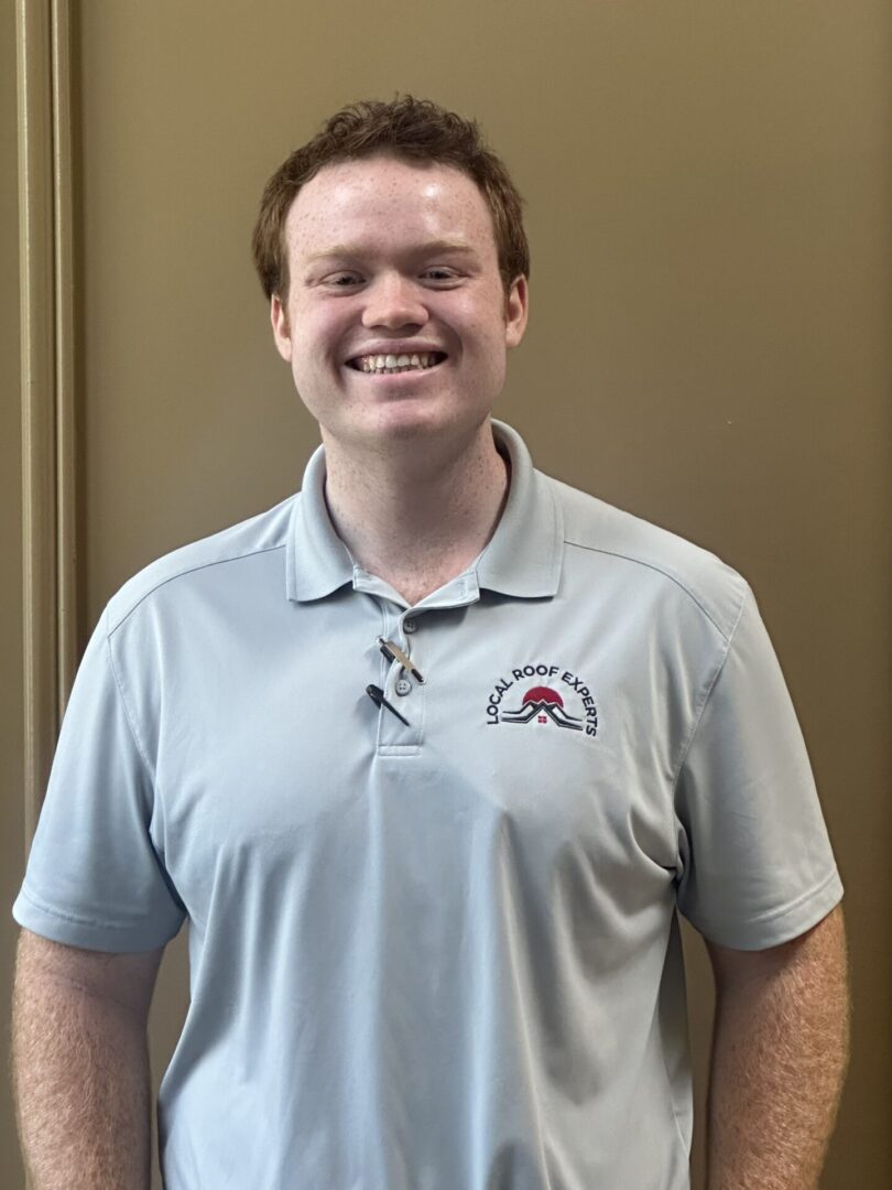 A man in a gray shirt smiling for the camera.